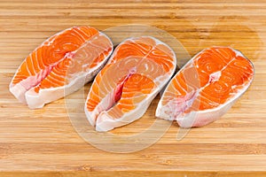 Uncooked steaks of arctic char on the wooden cutting board