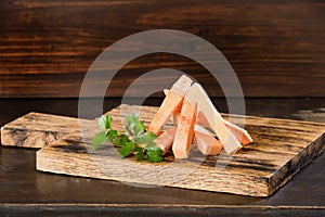 Uncooked sweet potato slices with pepers chilli, tomatoes and greenery on a dark wooden board background.