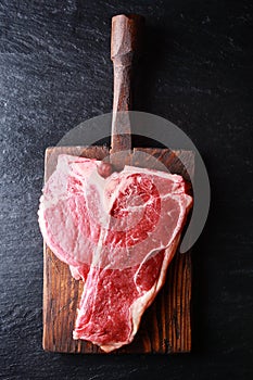 Uncooked t-bone steak on a wooden board