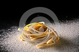 Uncooked traditional hand - rolled durum wheat pasta Pici of Tuscany, black background