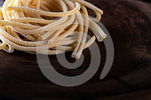 Uncooked traditional hand - rolled durum wheat pasta Pici of Tuscany, wooden rustic background