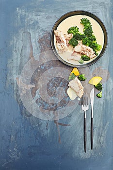 Uncooked white fish with bechamel sauce and broccoli