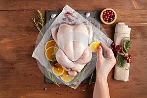 Uncooked whole chicken with oranges and rosemary ready for baking