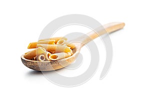 Uncooked whole grain pasta isolated on white background. Raw penne pasta on spoon