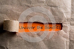 Uncover The Benefits message in letter or note, appearing behind ripped brown paper of envelope