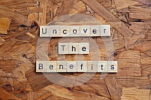 Uncover the benefits text on wooden square, business quotes.