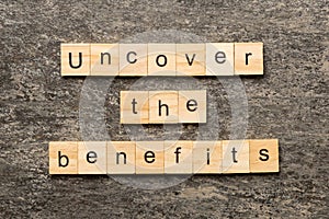 uncover the benefits word written on wood block. uncover the benefits text on table, concept