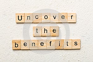 uncover the benefits word written on wood block. uncover the benefits text on table, concept