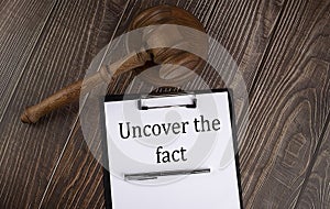 UNCOVER THE FACT text on paper with gavel on wooden background