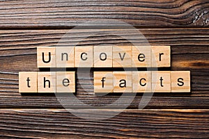 Uncover the fact word written on wood block. uncover the fact text on table, concept