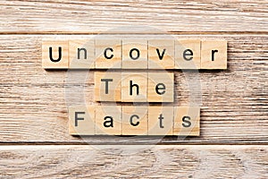 Uncover the fact word written on wood block. uncover the fact text on table, concept