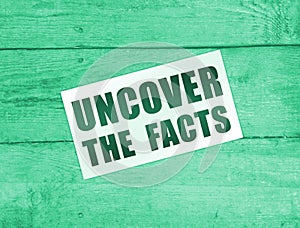 Uncover the Facts card on wooden background. Social concept. Business concept