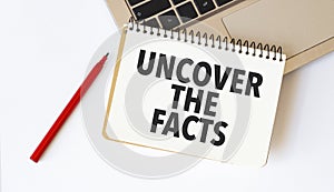 uncover the facts on notebook with red pencil and laptop
