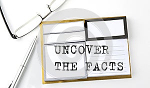 UNCOVER THE FACTS text on the sticky notes with glasses and pen, business concept