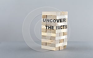 UNCOVER THE FACTS text on a wooden block , grey background