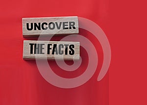 Uncover the facts word wood blocks on red. Fake or real news concept