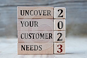 UNCOVER YOUR CUSTOMER NEEDS 2023 - words on wooden blocks on gray background