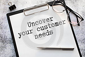 Uncover Your Customer Needs . gray and yellow background. text on white notepad paper.