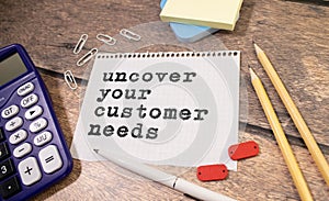 Uncover Your Customer Needs . gray and yellow background. text on white notepad paper