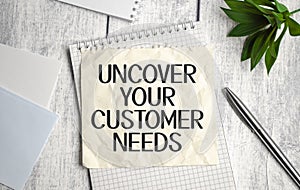 uncover your customer needs text on white notepad