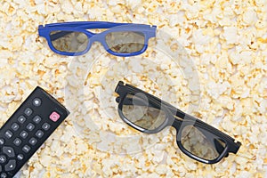 uncovered fried popcorn, close-up, as a background with a pair of 3D glasses and a TV remote control