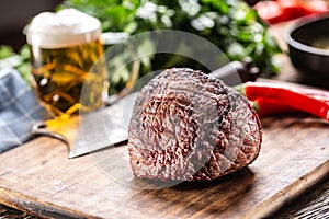 Unctut piece of pan-seared rump steak on a chopping board with a beer