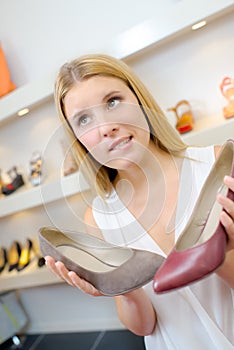 Undecided lady holding two shoes