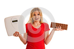 Undecided woman holding scale and chocolate uncertain wether to
