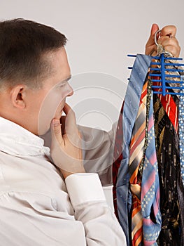 Undecided young man looking to a lot of neckties