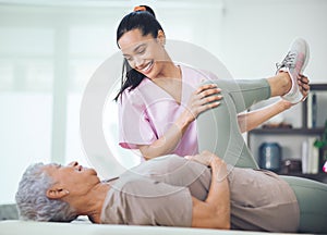 Undefeated compassion. an older woman doing light exercises during a session with a physiotherapist inside.