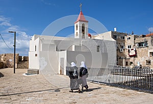 Undefined Arabian women walk next to St. John Baptist Catholic Church at old Acre city