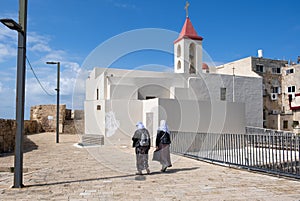 Undefined Arabian women walk next to St. John Baptist Catholic Church at old Acre city