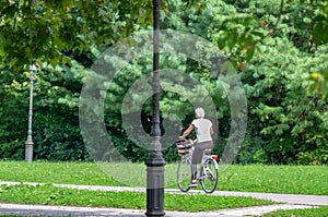 Undefined blonde girl ride on bicycle in Tivoli City Park at Slovenian capital, Ljubljana