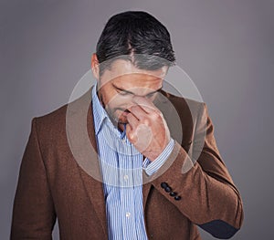 Under a bit of stress. Studio shot of a man deep in thought against a gray background.