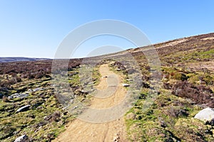 Under a blue sky a footpath rises and twists across Derwent Moor in Derbyshire