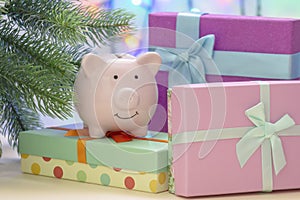 Under the Christmas tree are boxes with gifts. On the box is a small pig piggy bank.