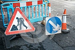 Under construction board sign on the closed road with arrow sign and traffic cone. Caution symbol under construction, work in