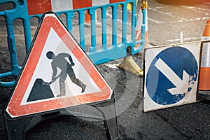 Under construction board sign on the closed road with arrow sign and traffic cone. Caution symbol under construction, work in