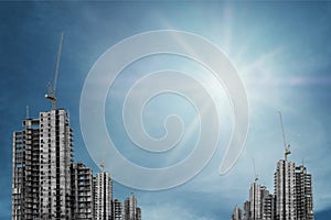 Under construction buildings with tower crane on blue sky with bright sun