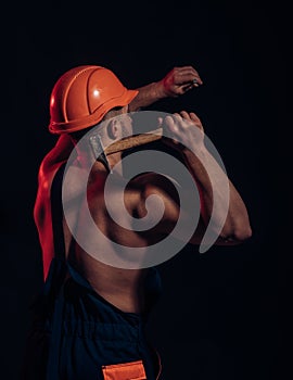 It is under construction. Hard worker use muscular strength. Construction worker hammer a nail. Muscular man builder at