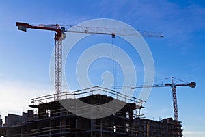 Under construction high-rise building with two cranes the background of blue sky