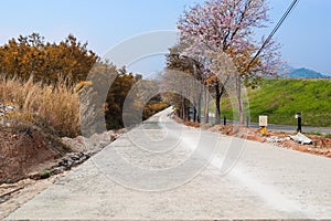 Under construction slope road with beautiful mountain view and pink flowers on trees