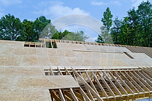 An under construction wooden home is being constructed on top of roof beams a construction site