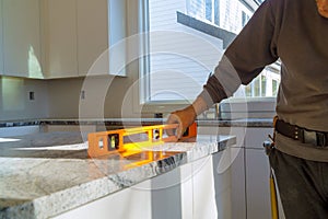 Under construction with worker checks the leveling of a granite slab for use a home kitchen remodel