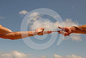 Under extreme tension. Athletic contest. Tug war is a sport. Male hands pull opposite ends of rope. Test of muscular