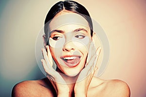 Under eye patches for dark circles and puffiness. Taking care of her skin. Pretty woman using eye patches spending time