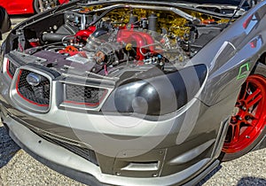 Under the hood of a car on exhibit with grey and red parts