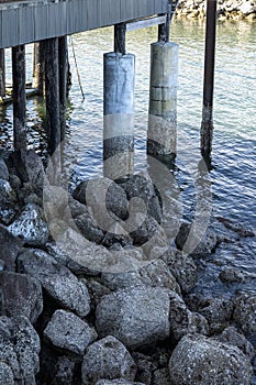 Under pier with supports, rocks, and water