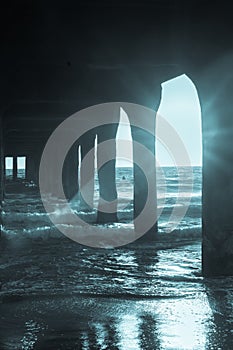 Under pier view to sea sun streams through structure at Manhattan Beach Pier.