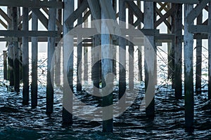 Under the Pier: Wooden Pillars and Crossbeams Over Sea Waters